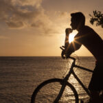 Silhouette of a man with a bike enjoying the sunrise